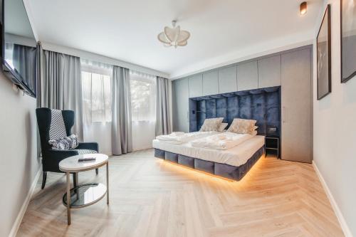 a bedroom with a large bed and a chair at Apartamenty Sun & Snow Ogrodowa in Sopot
