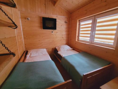 two beds in a wooden cabin with a tv in it at Domki drewniane pod Karpaczem in Mysłakowice