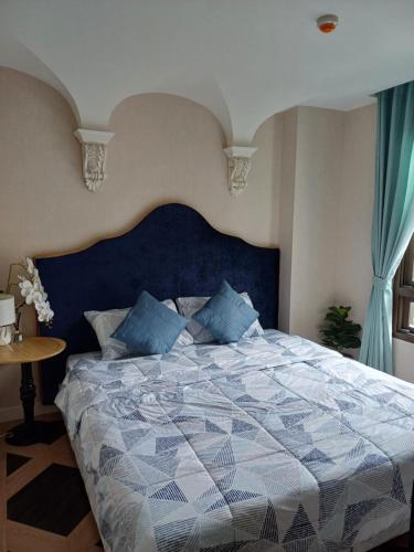 Espana condo resort Pattaya by BovyRentel في جومتين بيتش: غرفة نوم مع سرير كبير مع اللوح الأمامي الأزرق