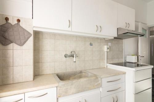 una cucina con lavandino e armadietti bianchi di Seafront Apartment in Piraeus a Pireo