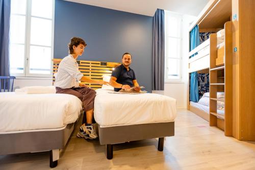 two people sitting on beds in a bedroom at The People - Marseille in Marseille