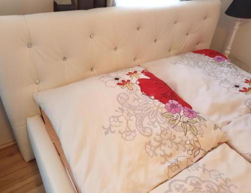 Una cama blanca con una manta floral. en Pension Birgit, en Rothenburg ob der Tauber
