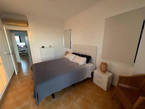 a bedroom with a bed and a chair at Triplex Meloneras-Amplio,soleado in Maspalomas