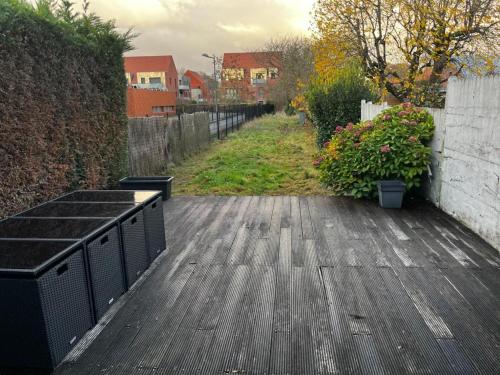 um deque de madeira com cerca e algumas plantas em Un cocon entre ville et nature em Annappes