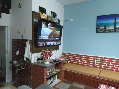 カラグアタトゥーバにあるCasa Caraguatatubaの壁にテレビが取り付けられたリビングルーム