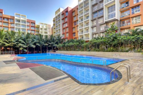 a swimming pool in front of some apartment buildings at Cozy 2BHK 4km from GOI airport - 15 min to Cansaulim Beach South Goa - Swimming pool access in Dabolim