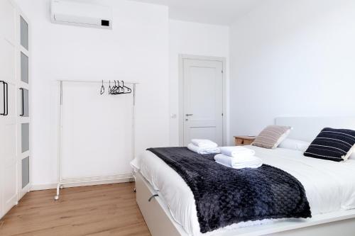 Dormitorio blanco con cama con manta negra en DeHomes - Bicocca Village 28, en Milán