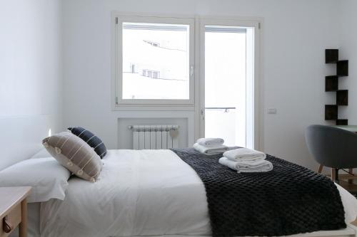 - une chambre blanche avec un lit et des serviettes dans l'établissement DeHomes - Bicocca Village 28, à Milan