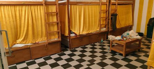 Pokój z 2 łóżkami piętrowymi i podłogą wyłożoną szachownicą w obiekcie Moon Dance Hostel and Cafe w mieście Pushkar