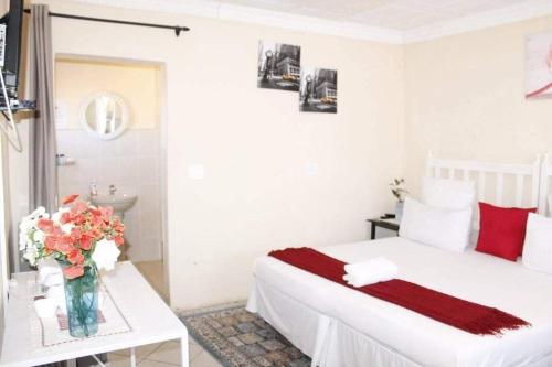 a bedroom with a bed and a vase of flowers on a table at RIO GUESTHOUSE in Maseru