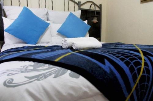 a bed with blue and white sheets and blue pillows at RIO GUESTHOUSE in Maseru