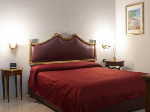 una camera da letto con un letto con copriletto rosso e due tavoli di Hotel Serena a Napoli
