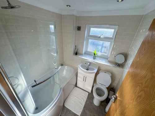 a bathroom with a tub and a toilet and a sink at One Bedroom Flat - Free Parking in Silverstone