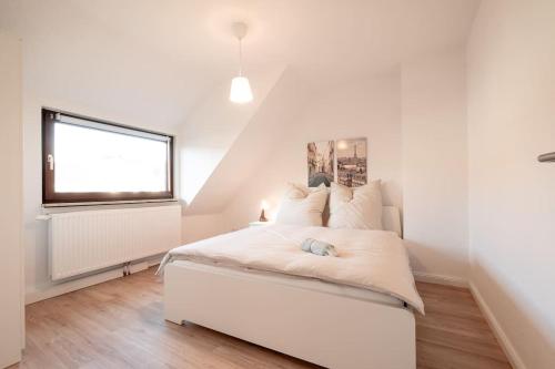 a white bedroom with a white bed and a window at Sehr schöne Wohnung für 6 Pers. in Bremen