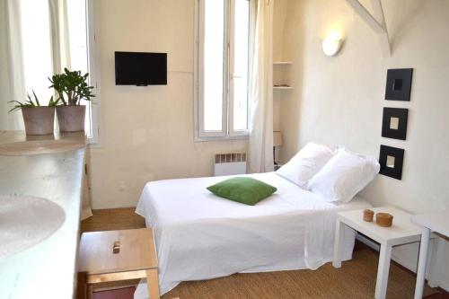 a bedroom with a white bed with a green pillow at Studio des Cardeurs au coeur du centre historique in Aix-en-Provence