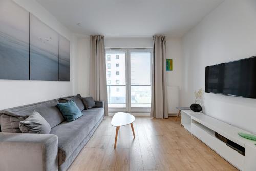 a living room with a couch and a flat screen tv at Apartament Nadmorskie Spektrum in Gdańsk