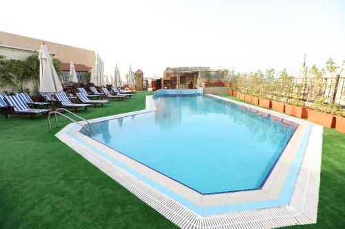 een groot zwembad op een gazon met stoelen en een parasol bij Cherry Maryski Hotel in Alexandrië