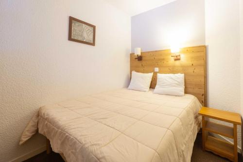 a small bedroom with a bed with a wooden headboard at Appartement Belle Plagne in La Plagne Tarentaise