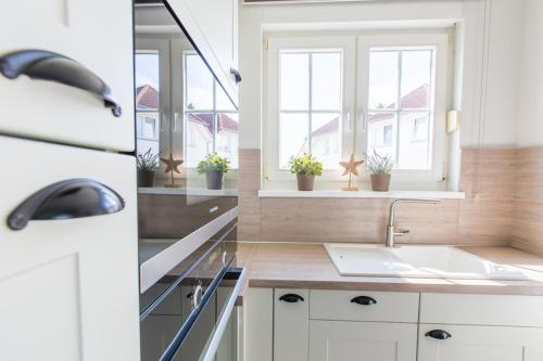 eine weiße Küche mit einem Waschbecken und 2 Fenstern in der Unterkunft Ferienwohnung Moin in Neddesitz