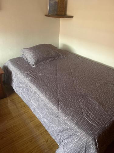 a bed with a gray comforter in a bedroom at Villadorado in Bogotá