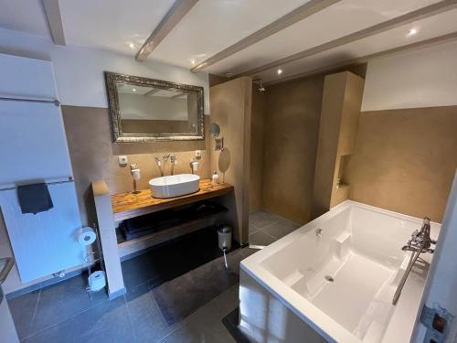 een badkamer met een groot bad en een wastafel bij Plompeblad Suite Giethoorn in Giethoorn