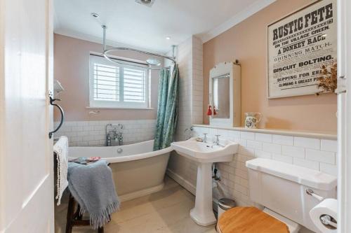 a bathroom with a tub and a sink and a bath tub at Quay Corner - Norfolk Cottage Agency in Cley next the Sea