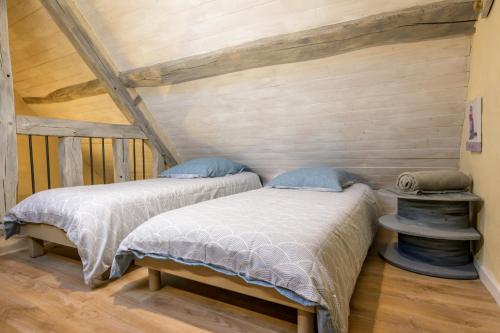 two beds in a room with wooden walls at Gîte Les Toisnières in Marigné-Laillé