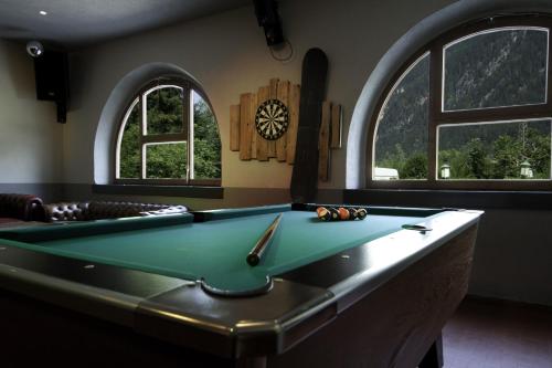 a pool table in a room with two windows at Hostel Chillertal in Mayrhofen