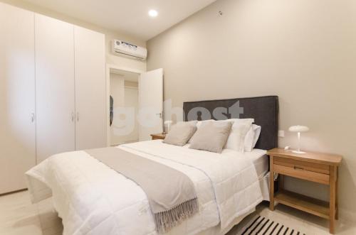 Un dormitorio blanco con una cama grande y una mesa en Beautiful And Relaxing Apartment At Villa Morra, en Asunción