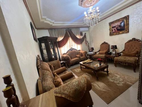 Jad apartment في إربد: غرفة معيشة مليئة بالاثاث والثريا