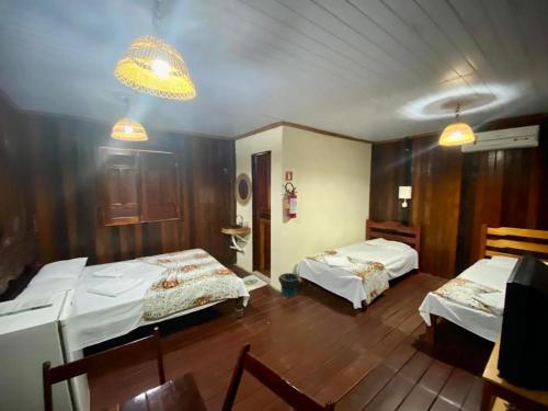 a room with two beds and a table and chairs at Pousada Encantos da Amazônia in Alter do Chao