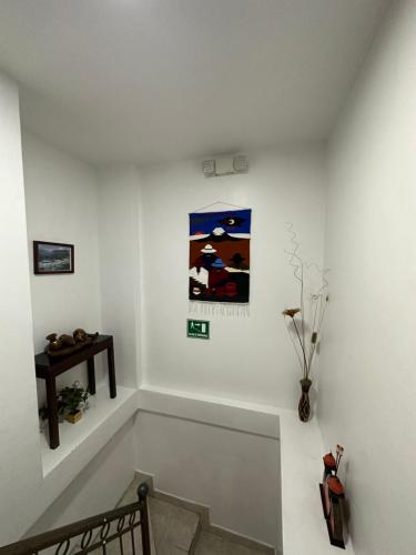 a white room with a bench and a painting on the wall at Hostal La Terraza in Quito