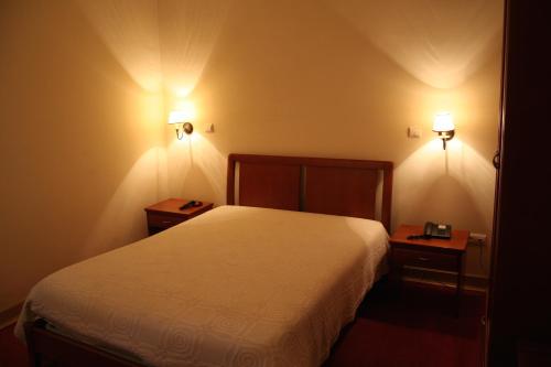 - une chambre avec un lit blanc et 2 tables de chevet dans l'établissement Residencial Dom Duarte, à Viseu