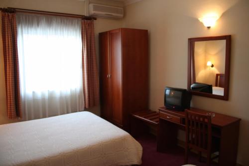 - une chambre d'hôtel avec un lit et un miroir dans l'établissement Residencial Dom Duarte, à Viseu