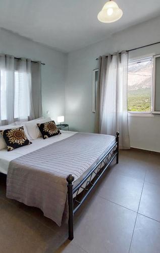 a bedroom with a large bed and a window at Harmony Cottage in Vasilikí