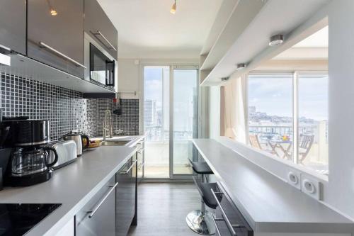 a kitchen with white counters and a large window at Vue mer Plage Catalans Vieux Port Clim - 2 chambres in Marseille