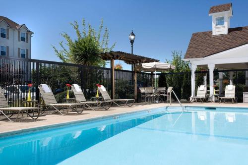 a swimming pool with lounge chairs and an umbrella at Sonesta Simply Suites Seattle Renton in Renton