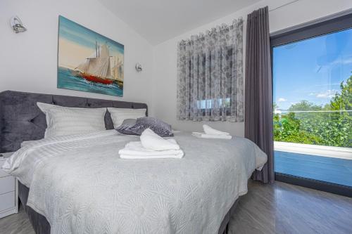 a bedroom with a white bed with a large window at VILLA NINA MALINSKA 150m FROM THE BEACH, SWIMMING POOL in Vantačići