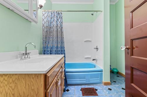 ein Badezimmer mit einem Waschbecken und einer blauen Badewanne in der Unterkunft Enchanting Echoes: Oasis Near the Falls in Niagara Falls
