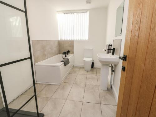 a bathroom with a tub and a toilet and a sink at The Church in Holyhead