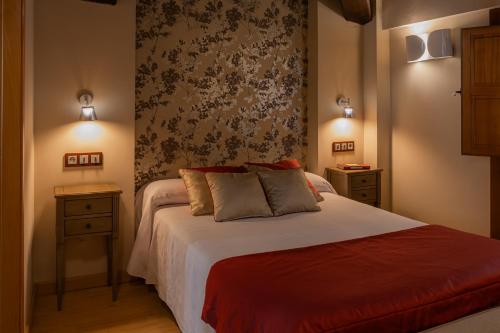 1 dormitorio con 1 cama con 2 mesitas de noche y pared en El Romero, en Hervás