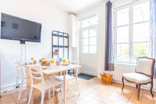 - un salon avec une table, des chaises et une télévision dans l'établissement Maison de Pêcheur - Terrasse priv. extérieure, à Étretat