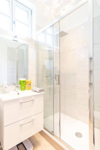 une salle de bain blanche avec une douche et un lavabo dans l'établissement Maison de Pêcheur - Terrasse priv. extérieure, à Étretat