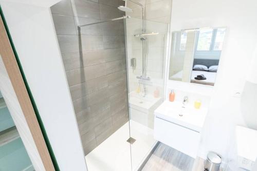 uma casa de banho branca com um chuveiro e um lavatório. em Le Station Angers - Gare - Hypercentre em Angers