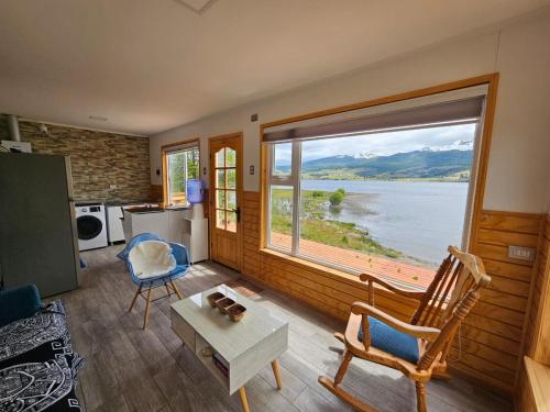 una sala de estar con una gran ventana con vistas al agua en Hermosa cabaña con orilla de playa y tinaja en Lago Frío en Coihaique