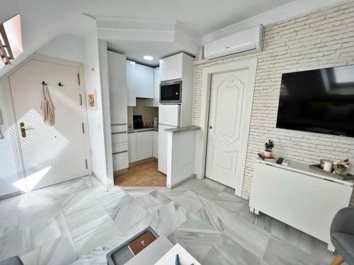 Una cocina blanca con un televisor y una puerta blanca. en Coqueto ático de playa, en Fuengirola