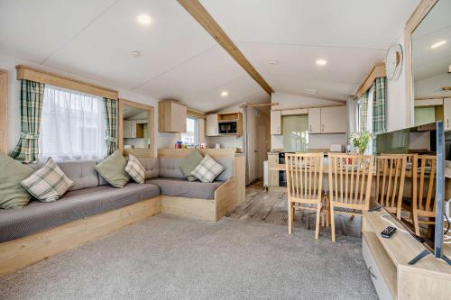 a caravan living room with a couch and a kitchen at Sea La Vie Lodge, Rockley Park Holiday Park, Poole, Dorset in Poole