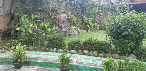 a garden with a statue and some plants at Mountain View Cottages & Villa Tangkahan in Tangkahan
