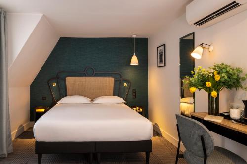 um quarto com uma cama branca e uma parede verde em Hotel De Suez em Paris
