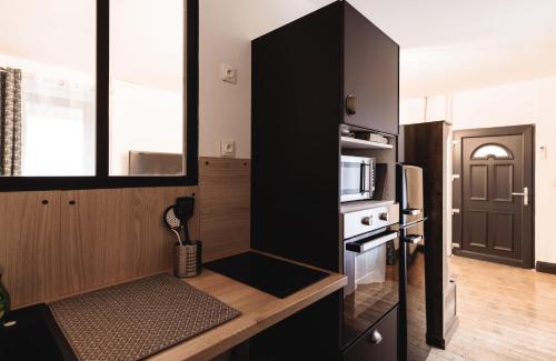 - une cuisine avec une armoire noire et un four micro-ondes dans l'établissement APPARTEMENT MAGINOT, à Bourg-en-Bresse